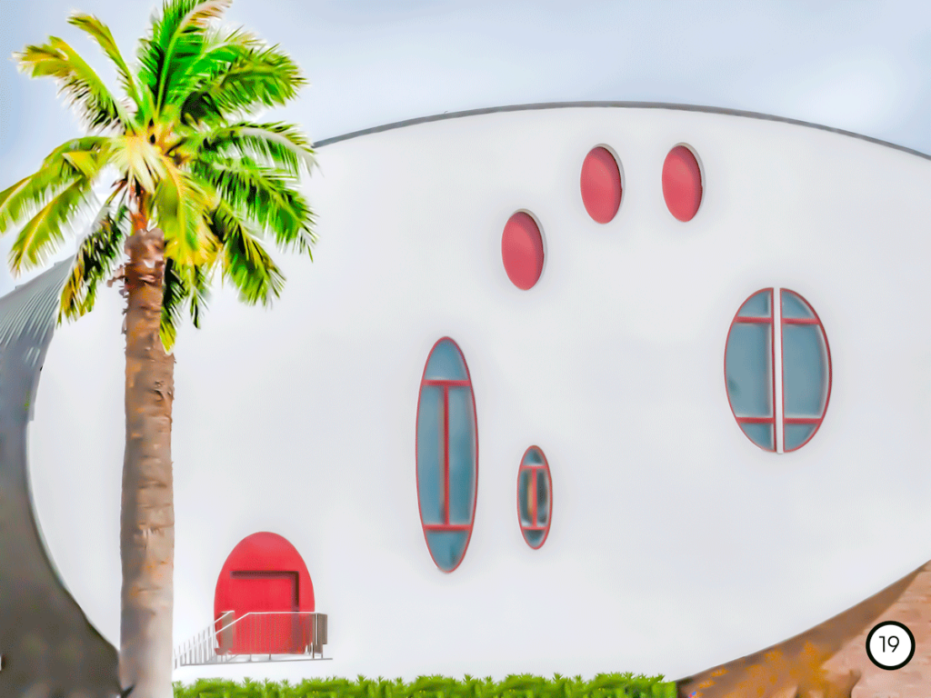 Photo d'une maison ronde avec des fenêtres rondes et rouges avec un palmier sur la gauche